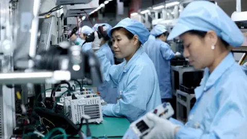 Reuters Workers wearing protective clothing work on a production line manufacturing smart automotive central control navigation products at a factory of Beidou Intelligent Connected Vehicle Technology Co. (BICV) in the High Tech Industrial Development Zone in Suqian, Jiangsu Province, China